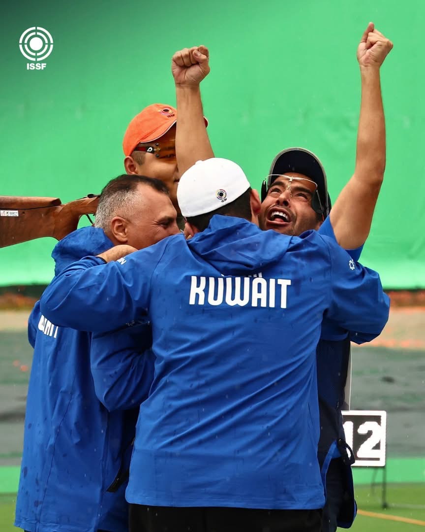 科威特射擊隊隊友穿著印有 KUWAIT 字樣的外套，圍在 Khaled 身旁一同慶祝
