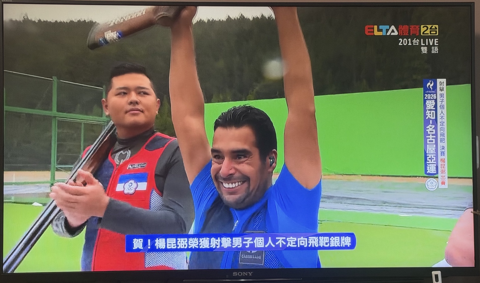電視轉播拍到楊昆弼在頒獎前鼓掌，旁邊的 Khaled 高舉雙手，字幕祝賀楊昆弼獲得銀牌